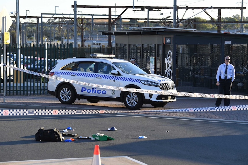 A police car and police tape in front of a train station.