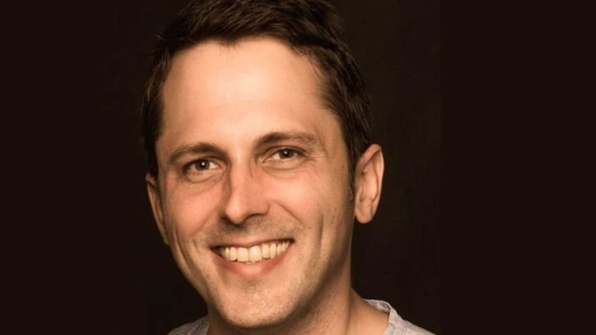 Headshot of Alex Turnbull, smiling, against a black background