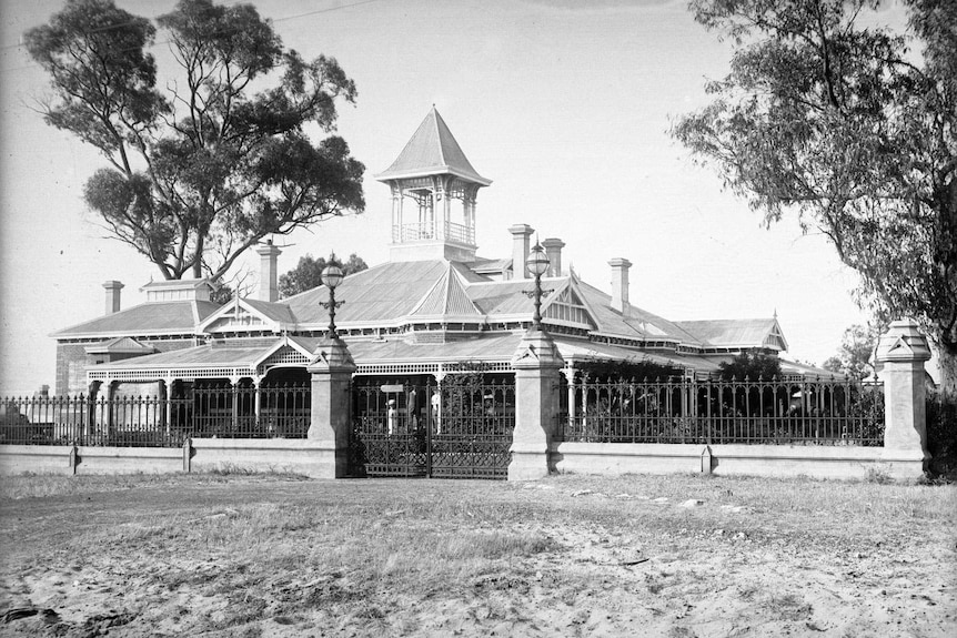 Black and white photo of grand federation house with garden wall, veranda and turret.