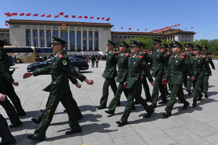 Paramilitary police officers dressed in green uniforms march in Tiananmen Square.