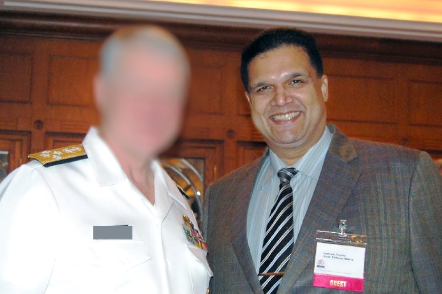 Francis and a US Navy officer with his face blurred smile for a photo.