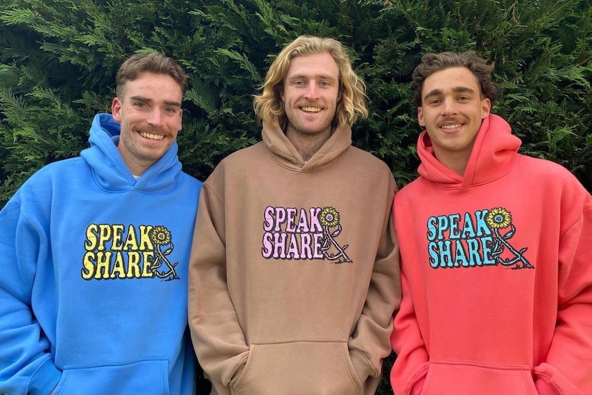 Three men wear bright and colourful hoodies