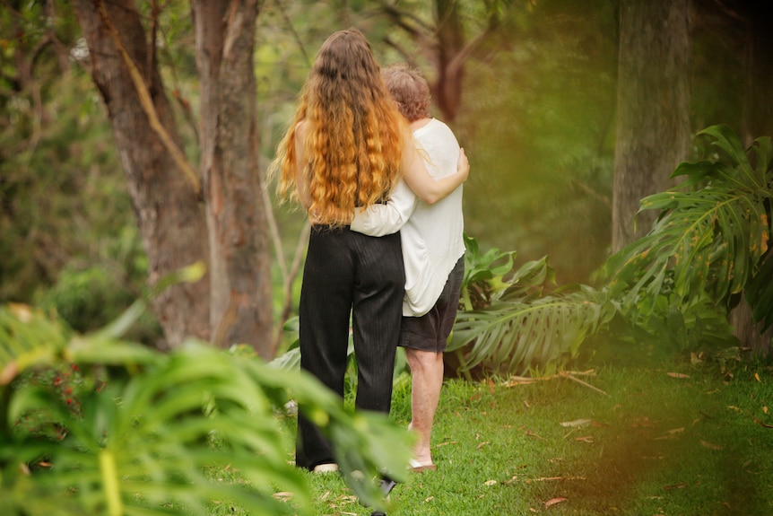 Unidentified woman stands outside with older woman