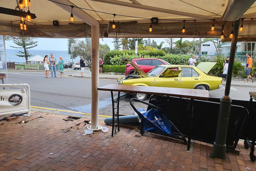 Damage to outdoor dining area of Moffat Beach Brewing Co restaurant on Queensland's Sunshine Coast with wrecked car in street.