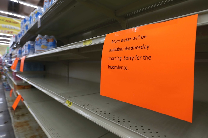 A empty supermarket shelf where water is normally placed.