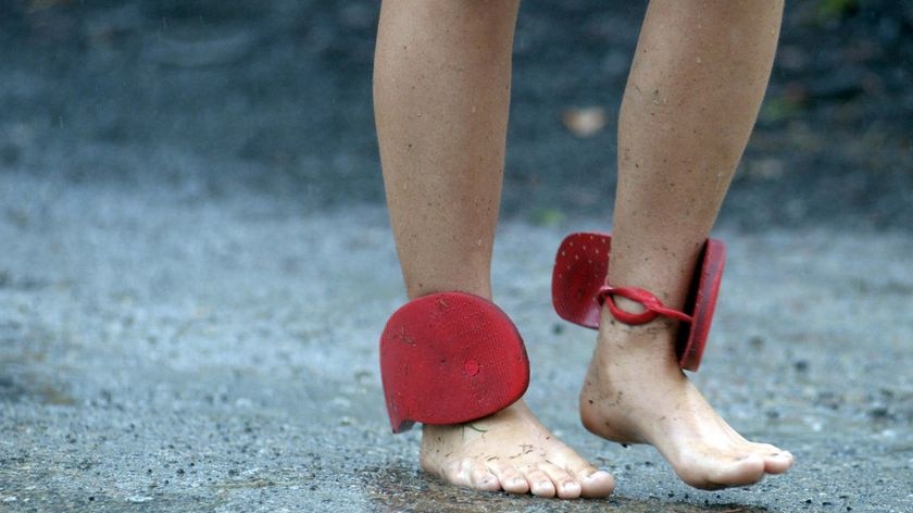 A festival-goer opts for bare feet and stores her thongs on her ankles during a downpour at the Woodford Folk Festival at Woodford, north of Brisbane, on December 27, 2007.
