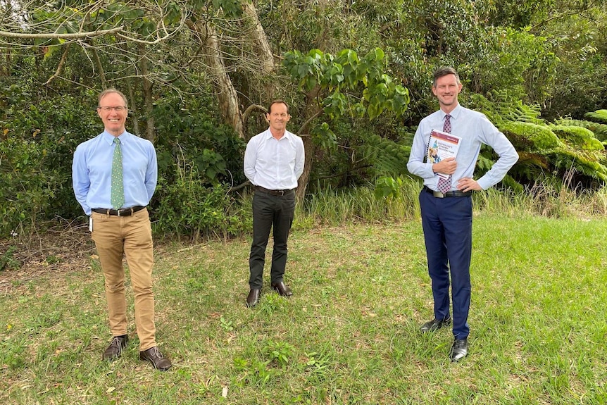 Three government officials in front of bushland.