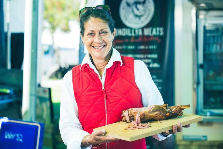 Woman holding a plate of cooked meat.
