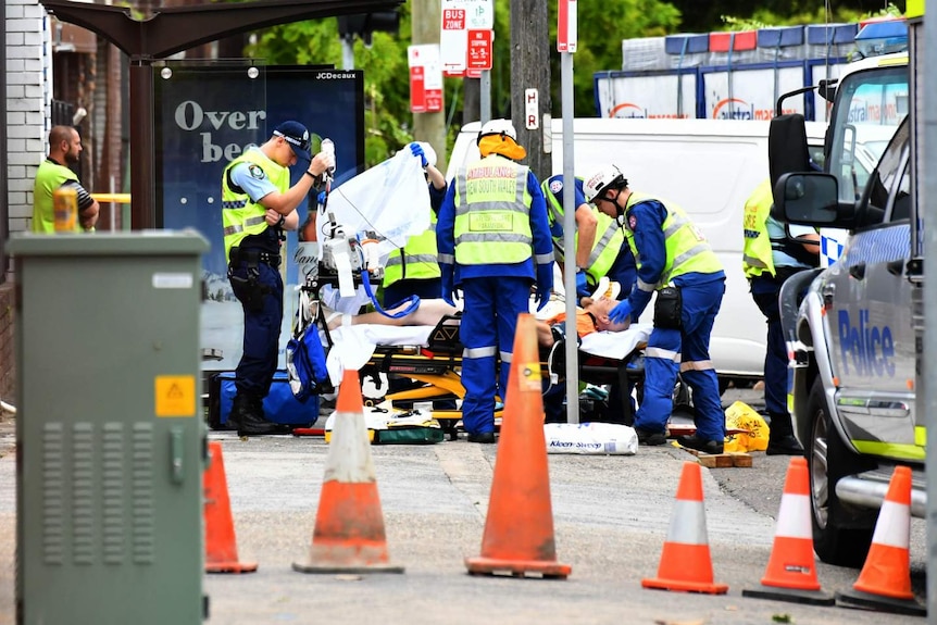 A man lies on a stretcher surrounded by other people.