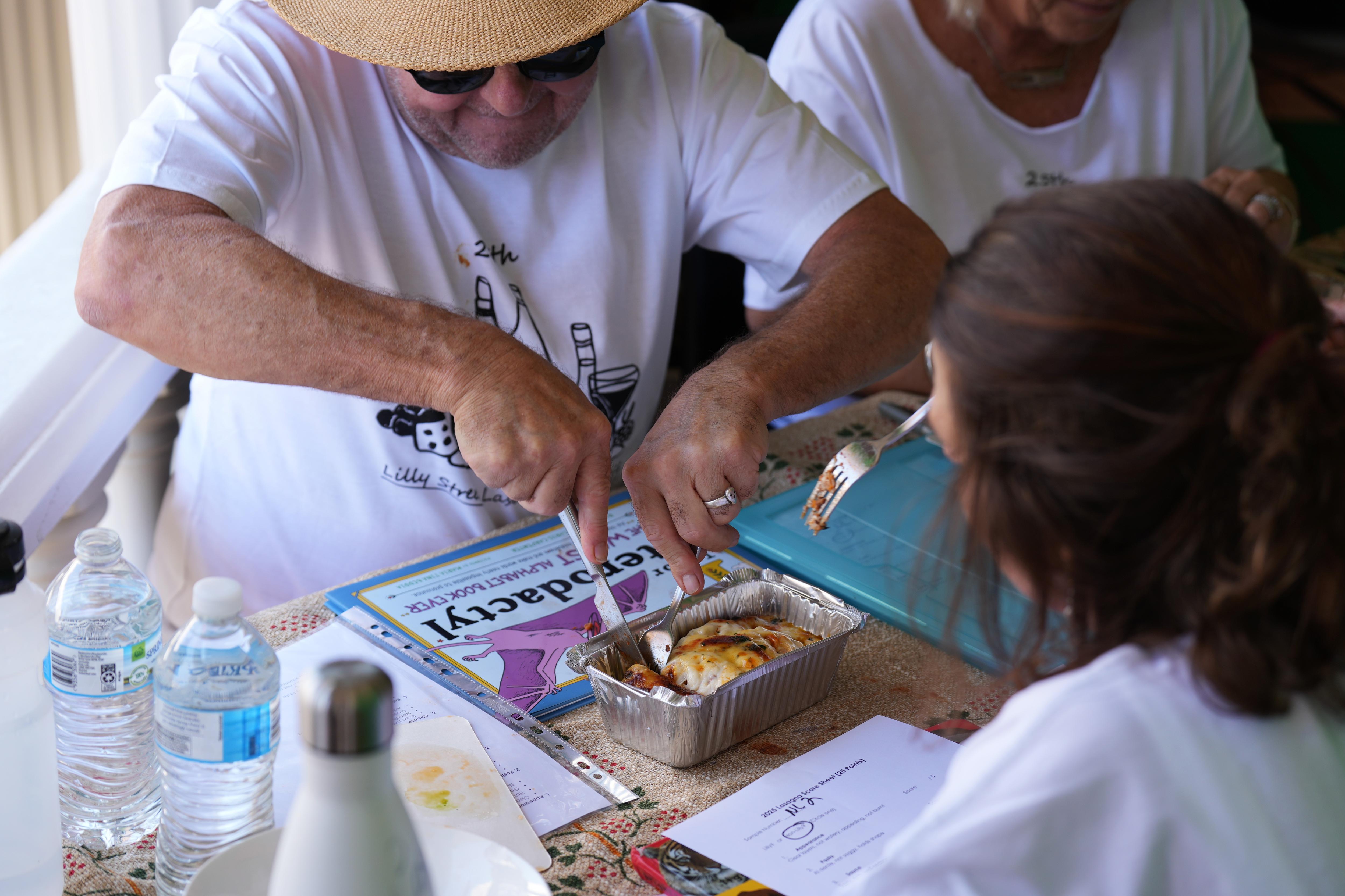 Un hombre corta un trozo de lasaña. 