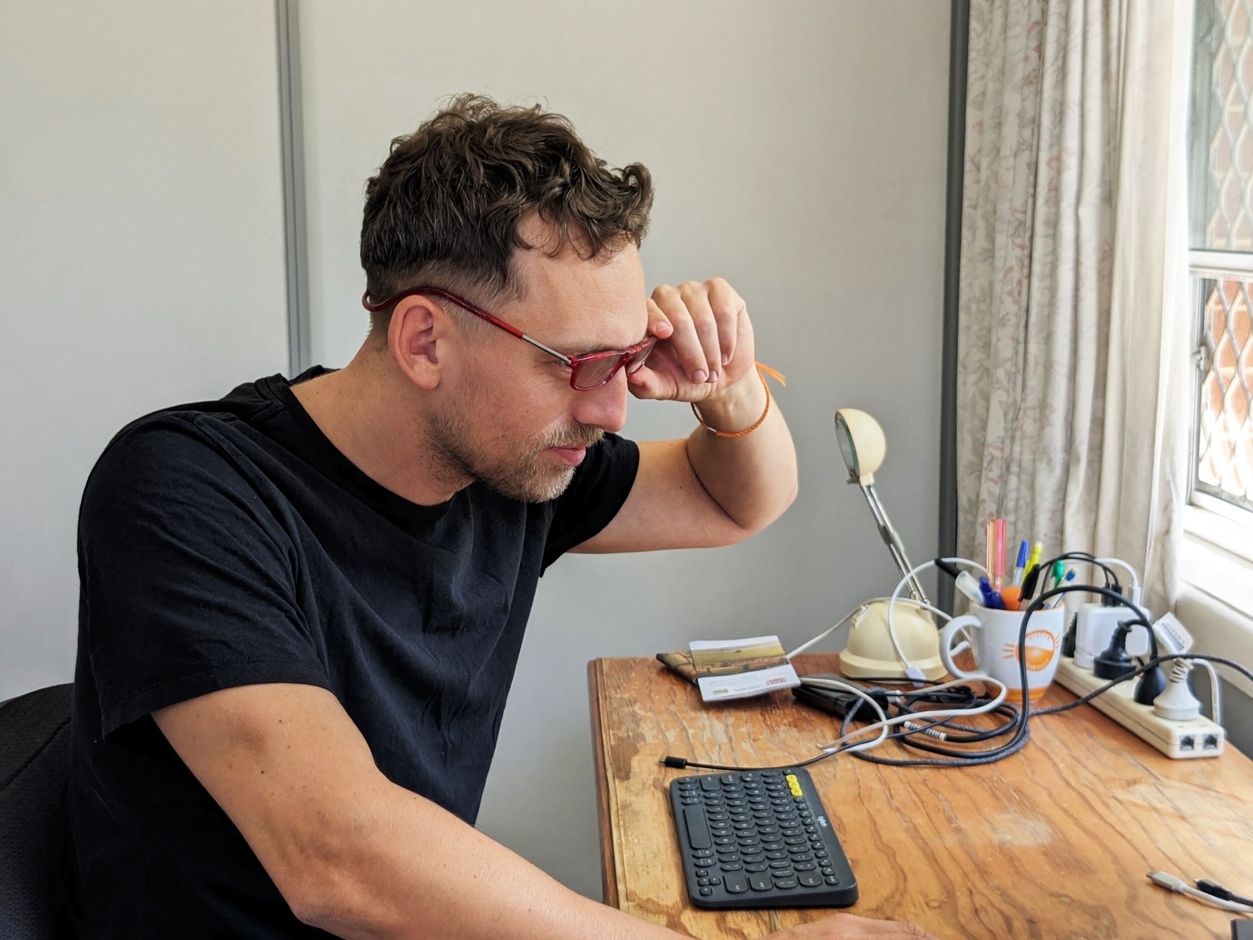 Kurt sits at his desk and adjusts his reading glasses as he takes a closer look at the screen of his laptop