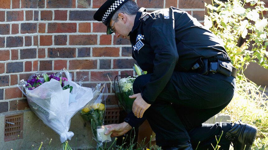 Policeman places candle outside shooting victims' home