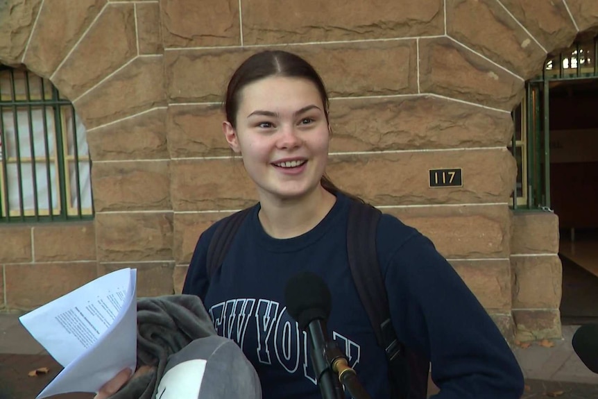 A young woman looking happy outside a hotel.