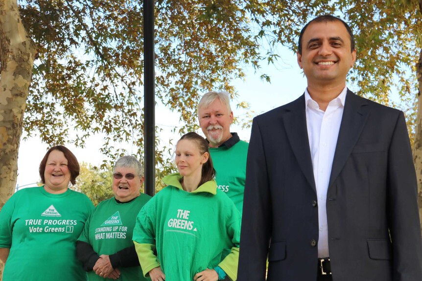 Muhammad Salman stands smiling at the camera in a suit with four supporters in green shirts alongside.