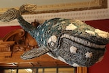 Large baleen whale made of fabric, rope and material suspended from room of ornate old room