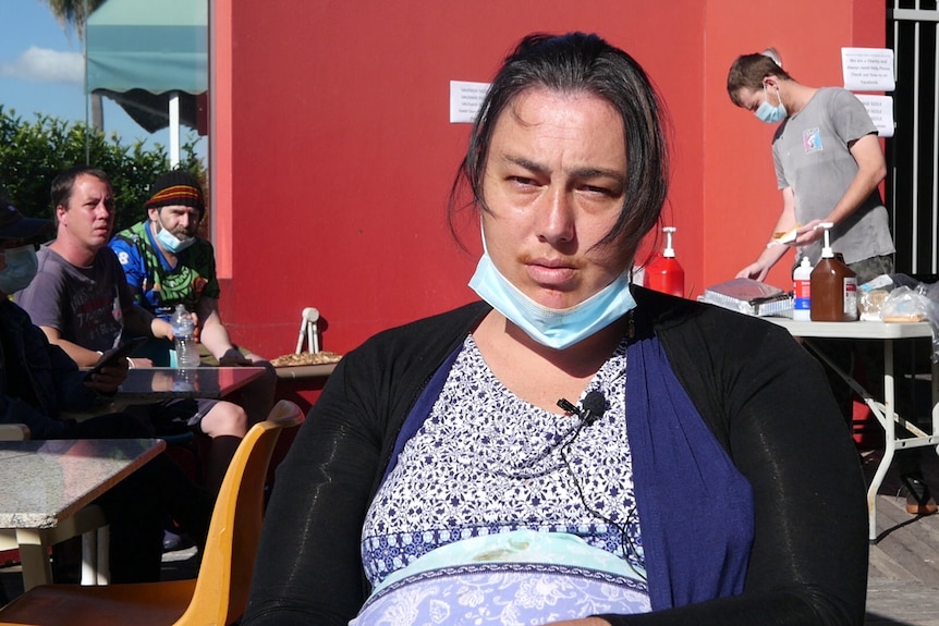 Woman with face mask under her chin at an outdoor barbecue.