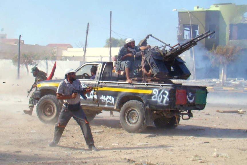 One man shoots a gun as a canon is fired from the back of a truck.