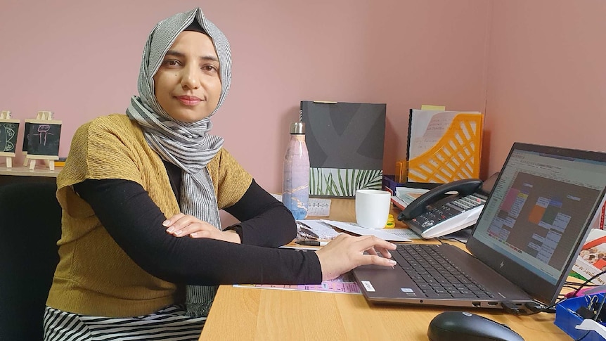 Annie Haider sits at her desk in front of her laptop and looks at the camera.