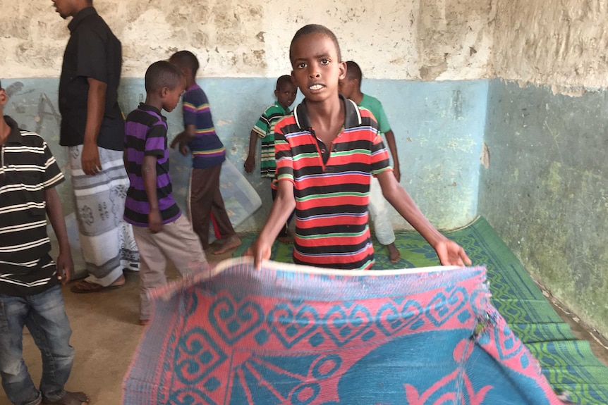 Boy sets up mat to sleep on