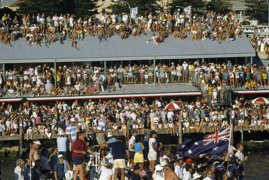People sitting on rooves to watch a boat race.
