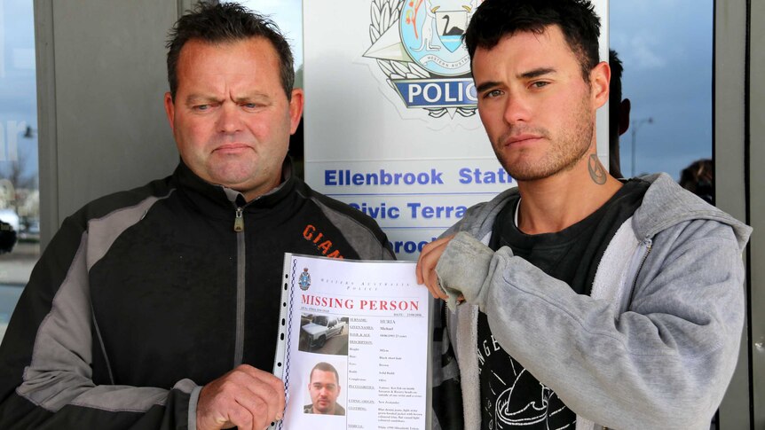 Mark and Tamati hold a missing person poster between them.