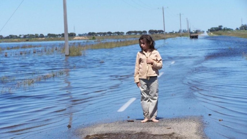 A girl stands at the edge of Victoria floodwaters