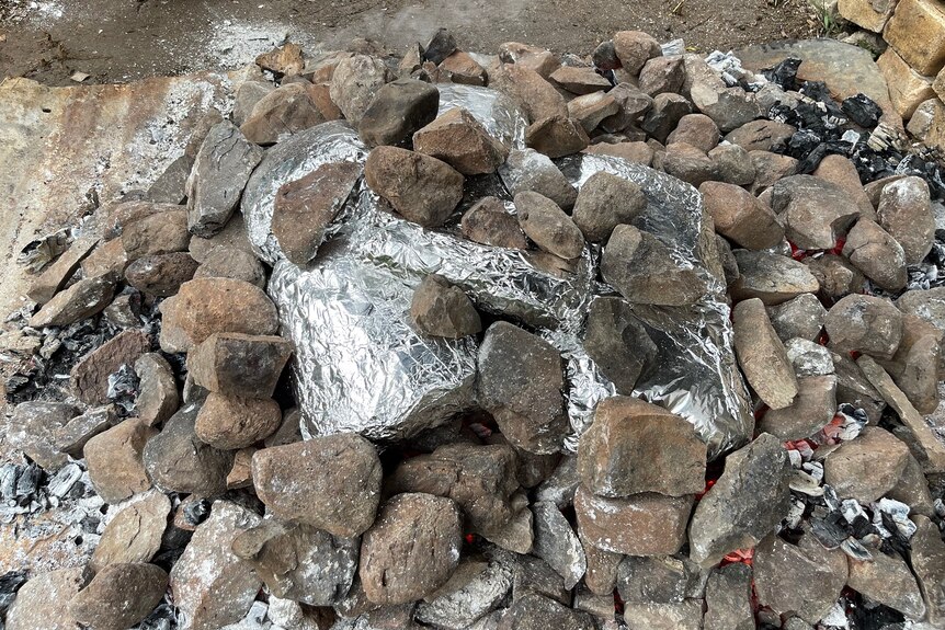 Meat wrapped in foil is placed on hot rocks.