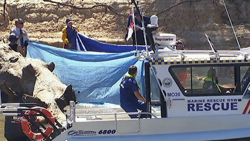 Police putting up blue tarps as they remove the body of a boy from the Murray River.