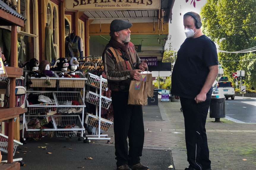 Bags are handed over in the street outside a shop.