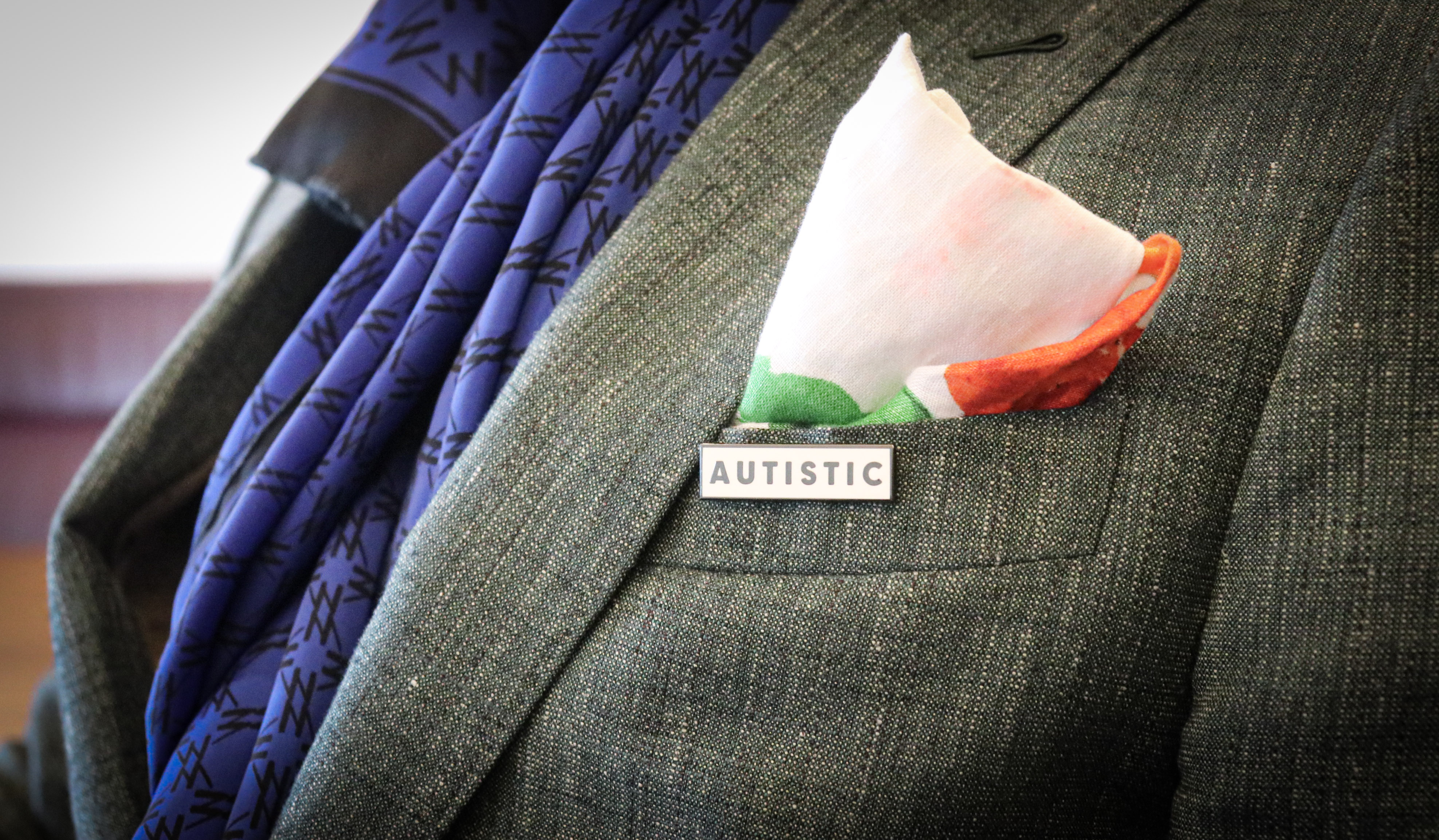 A man wearing a pin with that says autistic