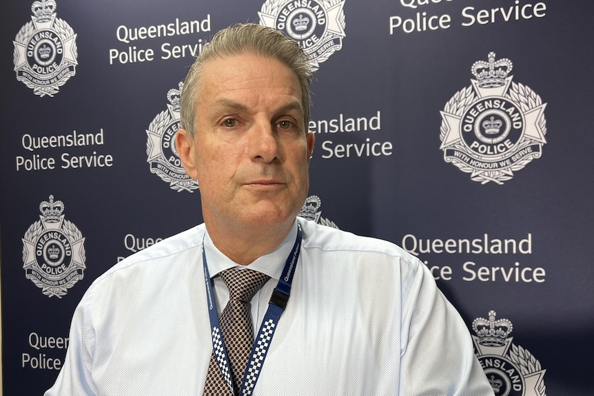 Darrin Shadlow stands in front of Queensland Police Service backdrop in the Mackay District Office. 