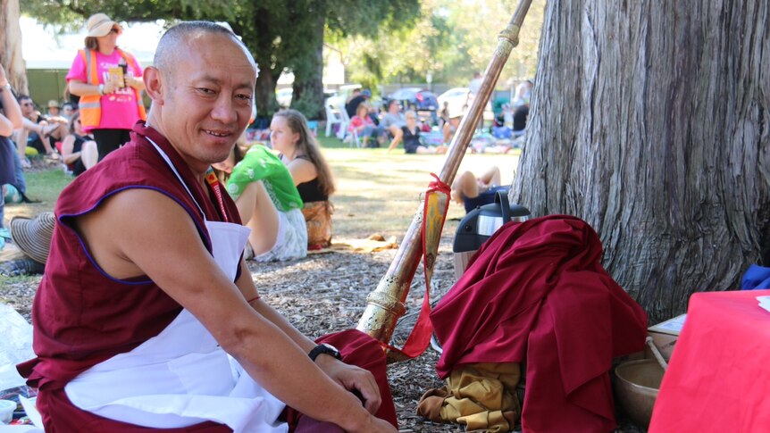 Monk rests under a shady tree in Botanic Park during Womadelaide