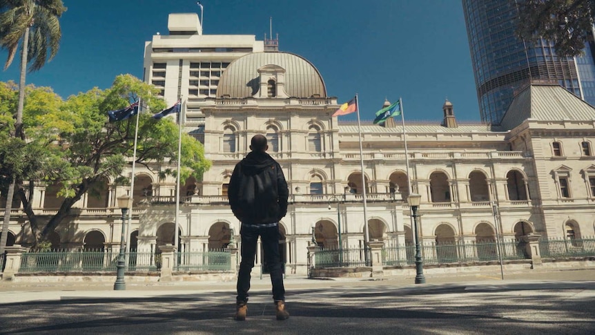 View of the back of Christiaan Van Vuuren as he stands in front of the Queensland parliament building