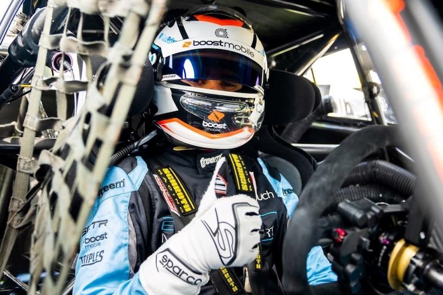 Driver in race car wearing helmet and racing suit