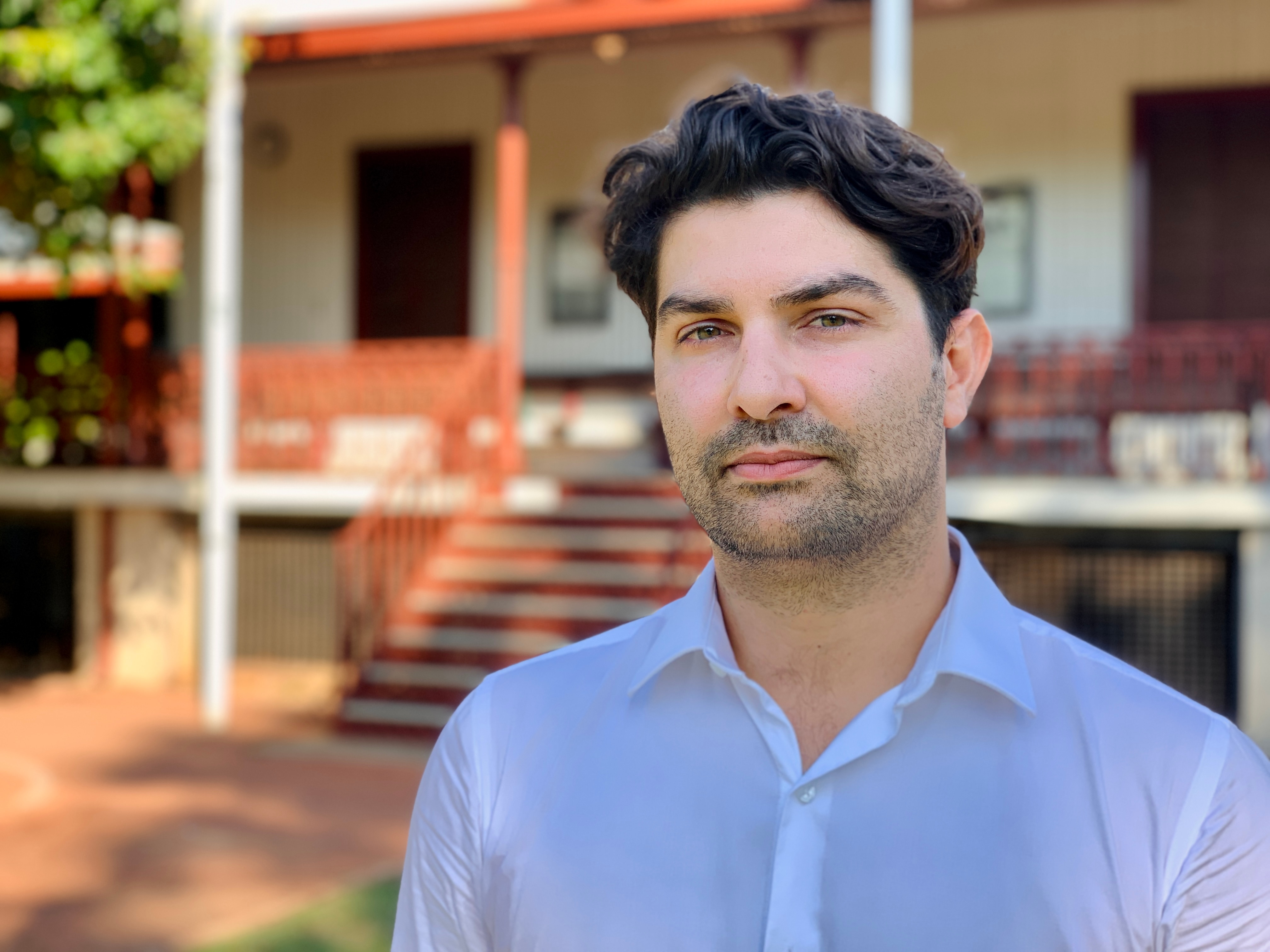 A portrait of Daniel Bavcevic looking serious and standing in front of the Legal Aid building in Broome 