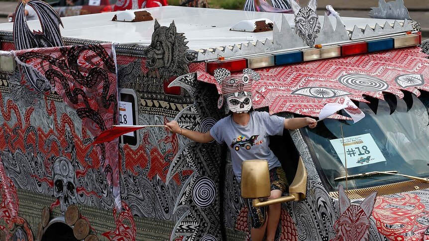 A paradegoer hangs out of a decorated car at the Houston Art Car Parade