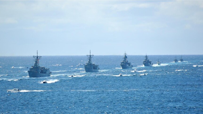 A line of warships make their way towards Sydney Harbour for the International Fleet Review.