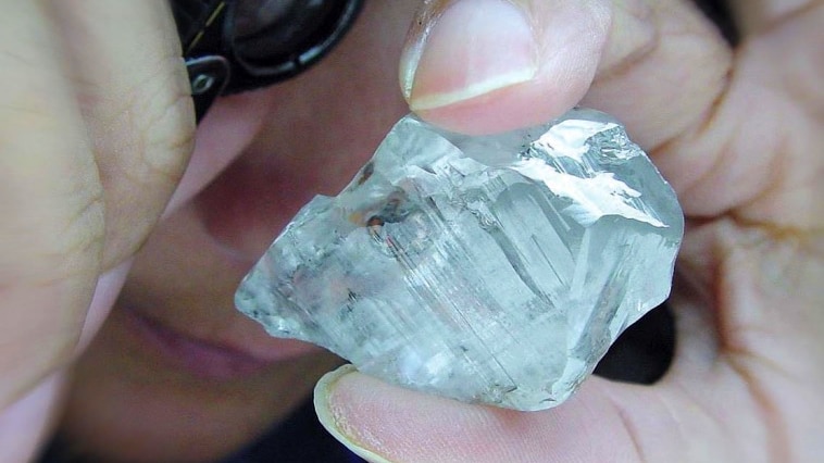 a large rough diamond being held by a hand.