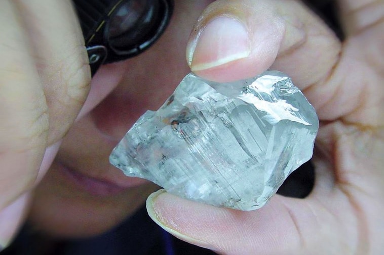 un gran diamante en bruto sostenido por una mano.