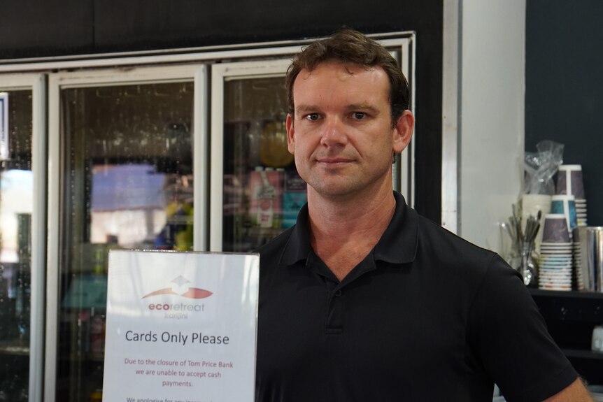 A man in a black polo stands behind a sign that says "Cards Only Please"