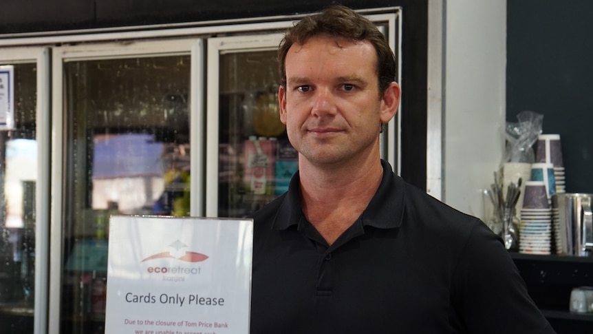 A man in a black polo stands behind a sign that says "Cards Only Please"