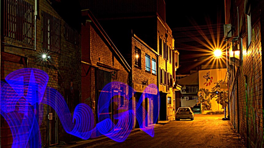 Splash of blue light in dark alleyway
