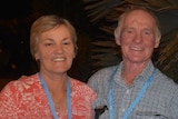 A smiling older couple wearing matching lanyards.