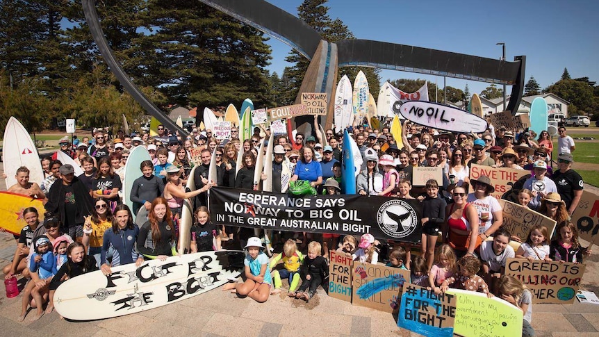 A crowd gathers holding signs