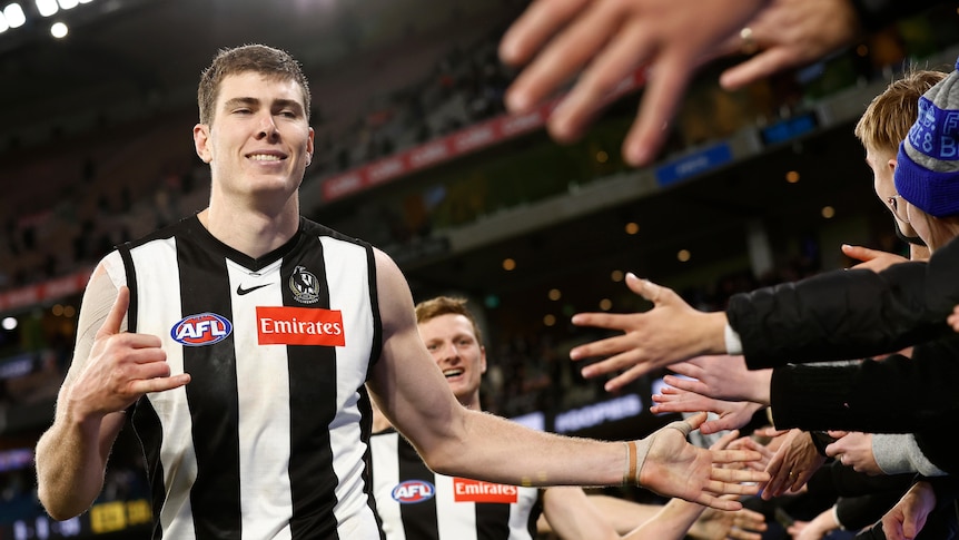 Mason Cox smiles while high-fiving Pies fans over the fence