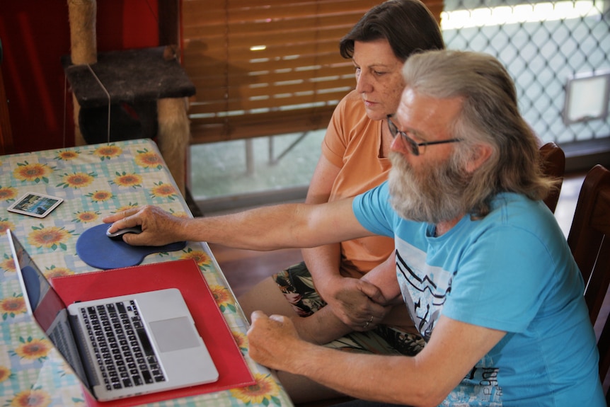 a man and a woman look at a laptop