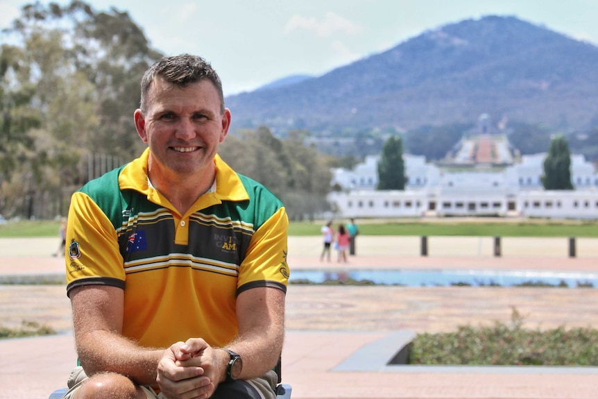 Garry Robinson looks at the camera, with Anzac Parade and the Australian War Memorial behind him.