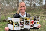 Woman looks at camera, smiling and holding onto a pollinator guide.