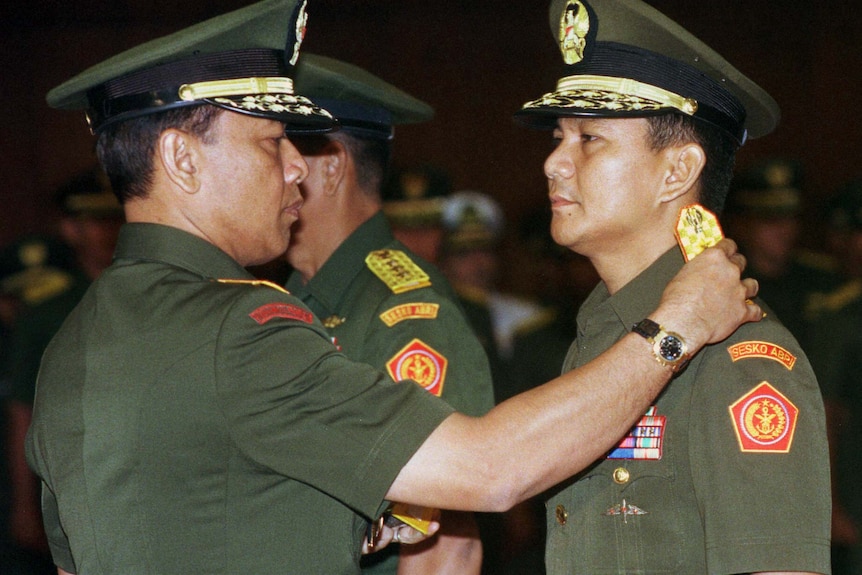 General Wiranto fixes the epaulets of Prabowo Subianto.