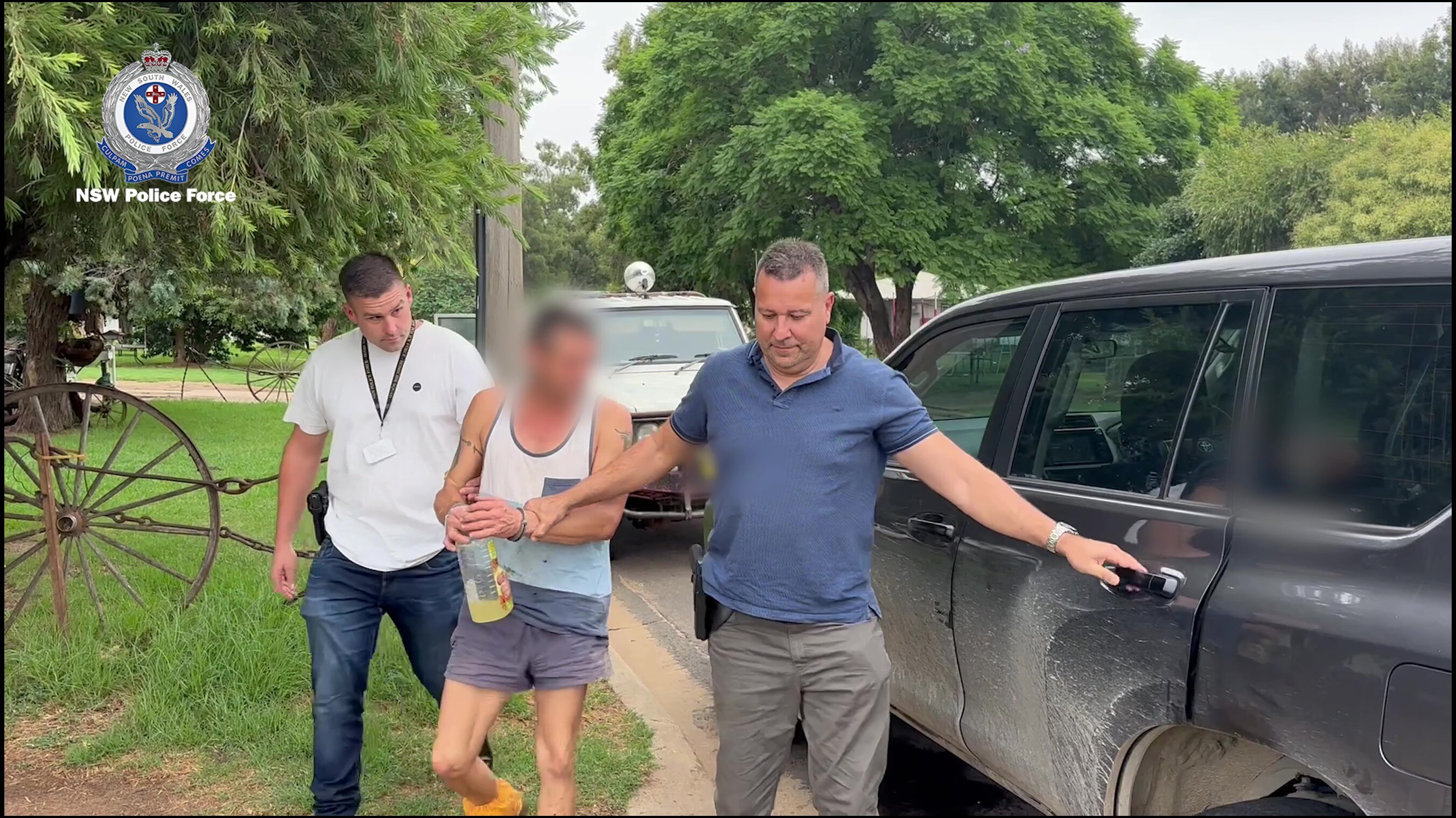 A man being escorted into a car by two police officers